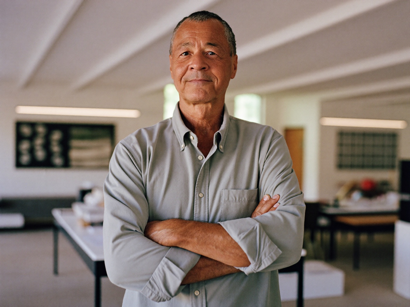 A man in his sixties still at work, arms folded in a bright office